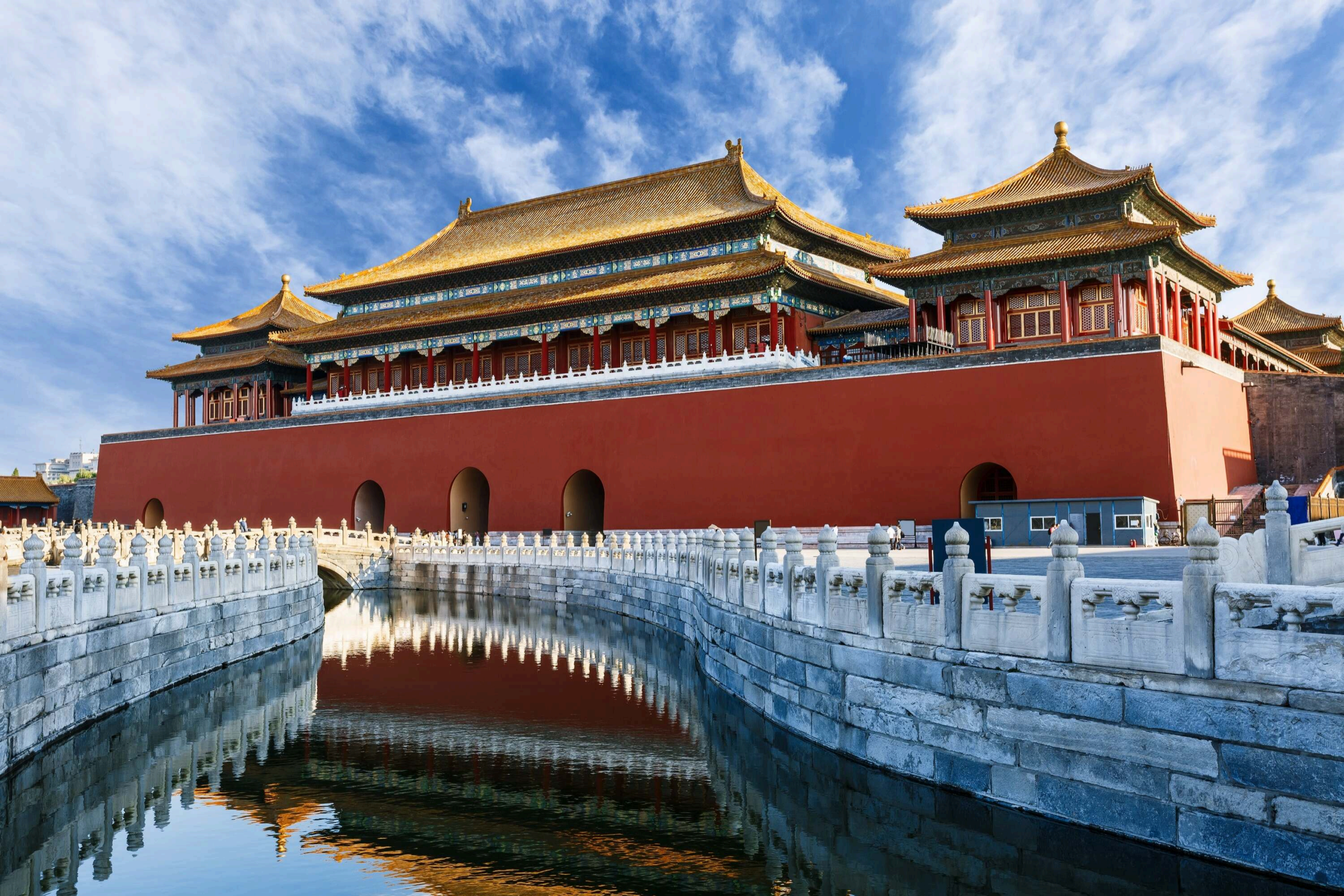 Red wall, golden roofs, white balustrades, and water inside the Forbidden City.