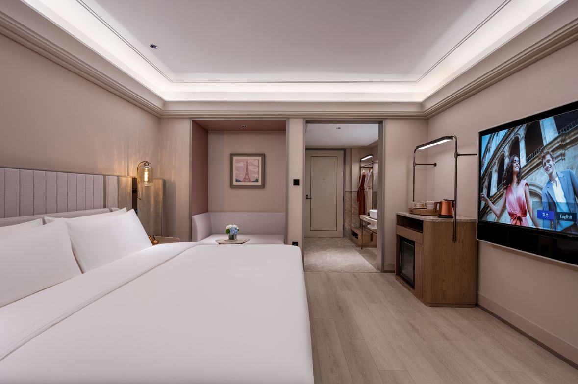 Contemporary Beijing hotel guest room with bed, television, and open vanity area.