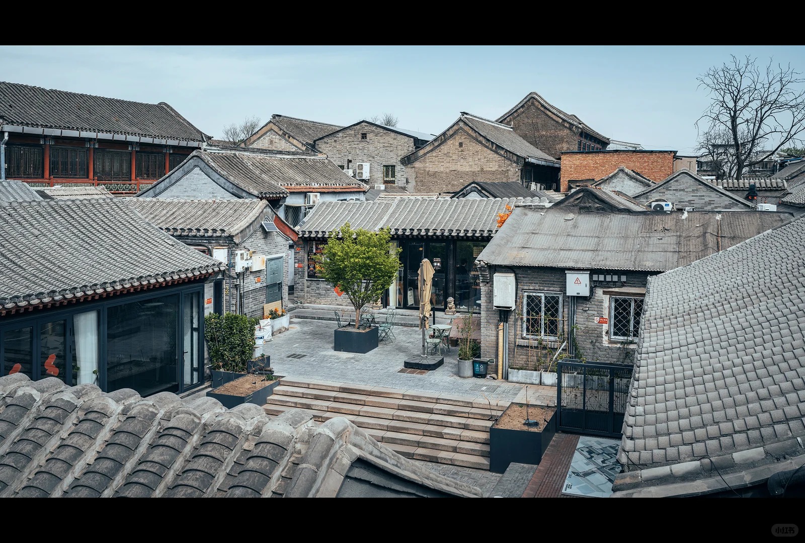 Traditional gray-tiled hutong rooftops surrounding a courtyard in Beijing.