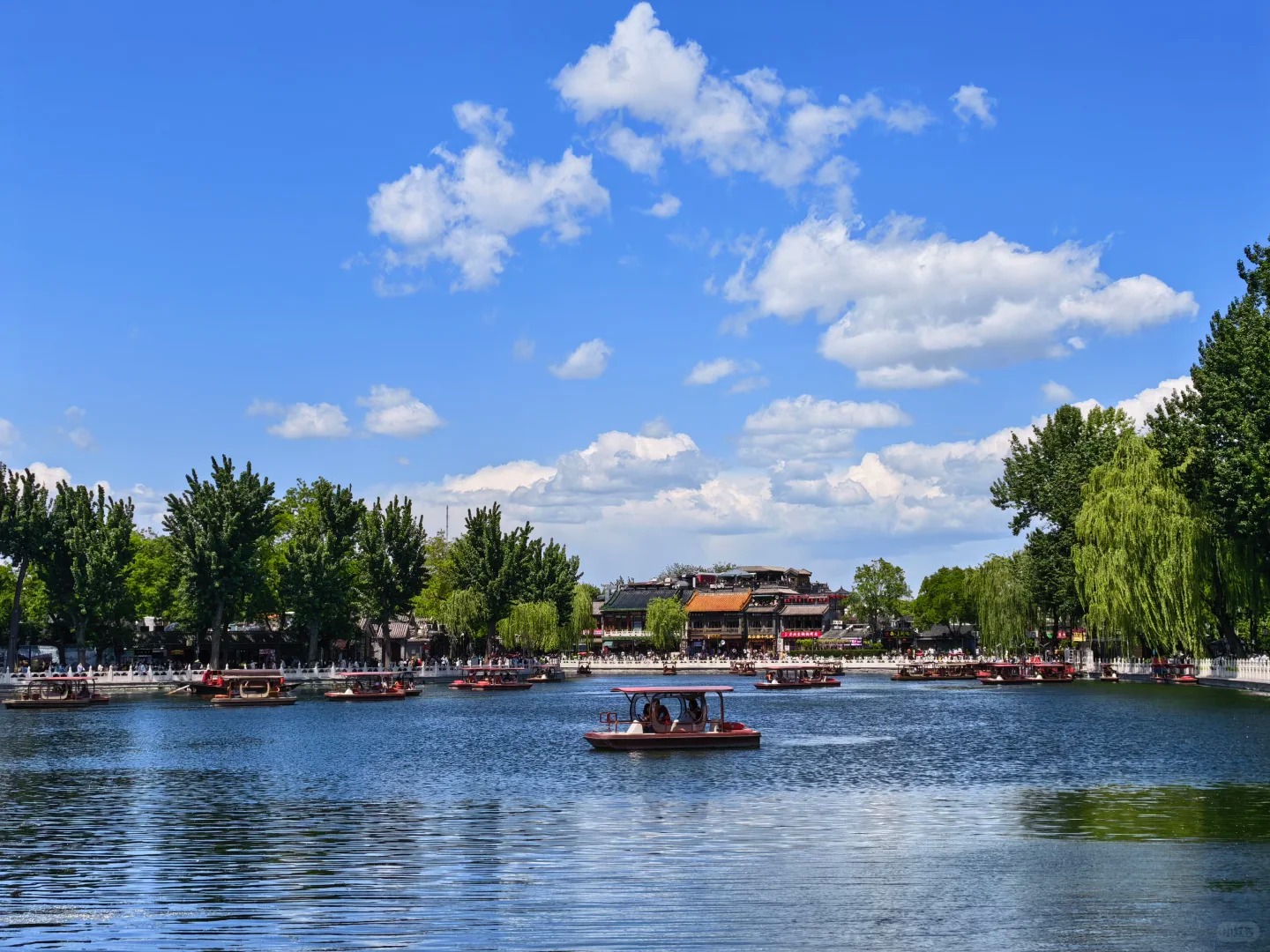 Pleasure boats on Shichahai lake beneath blue sky in Beijing.