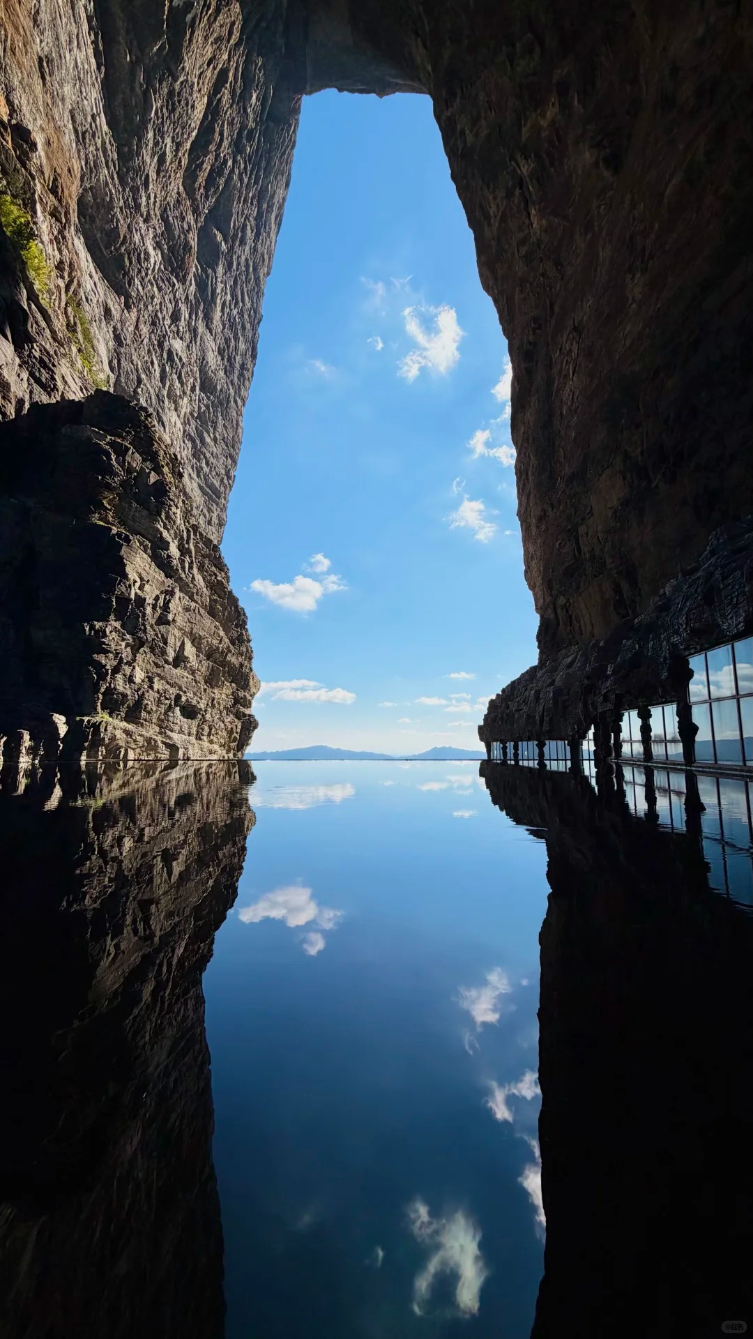 Blue sky and reflective water framed by the dark rock walls of Tianmen Cave.