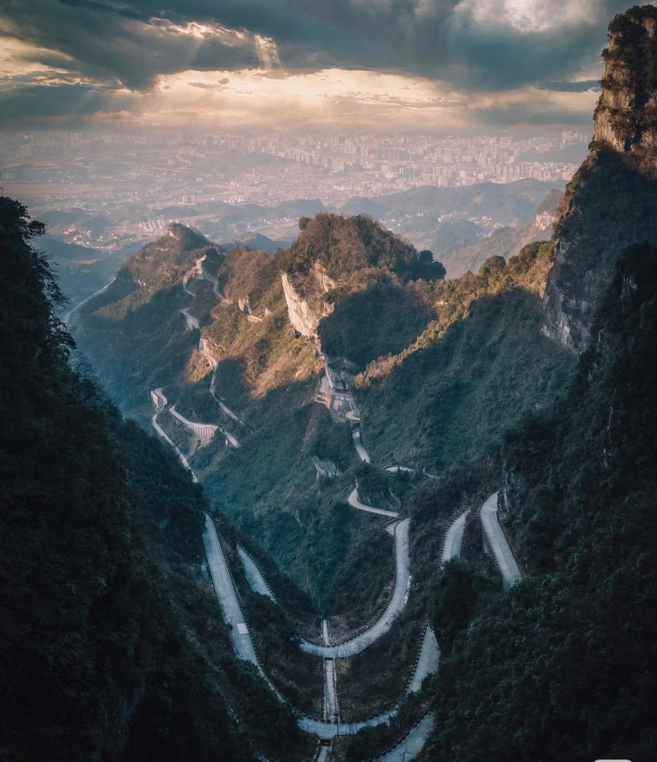 A winding mountain road with many hairpin bends climbing through Tianmen Mountain.
