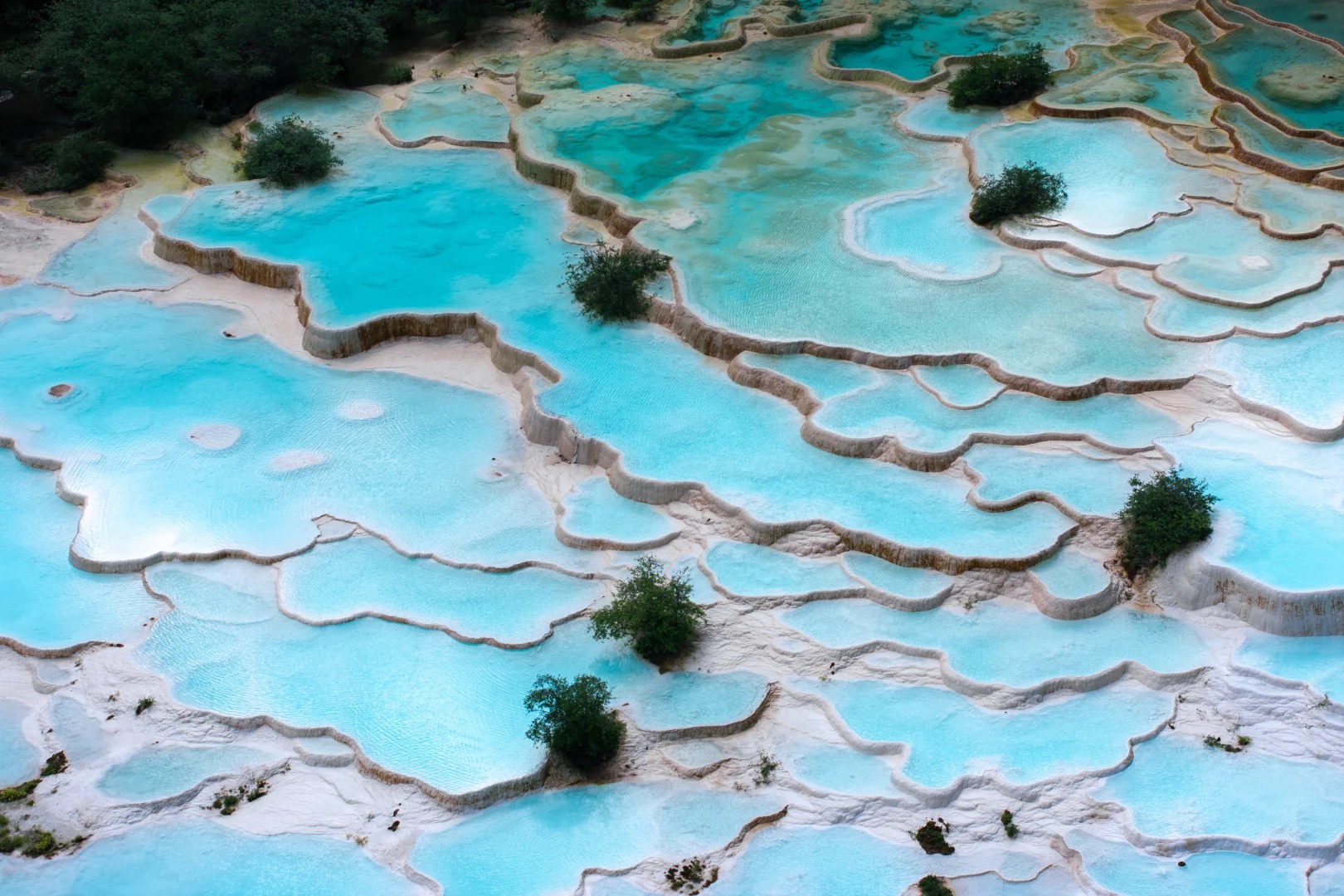 Tiered turquoise travertine pools with pale mineral edges at Huanglong in Sichuan.
